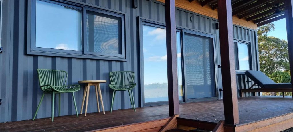 Converted shipping container cabin with deck and furniture